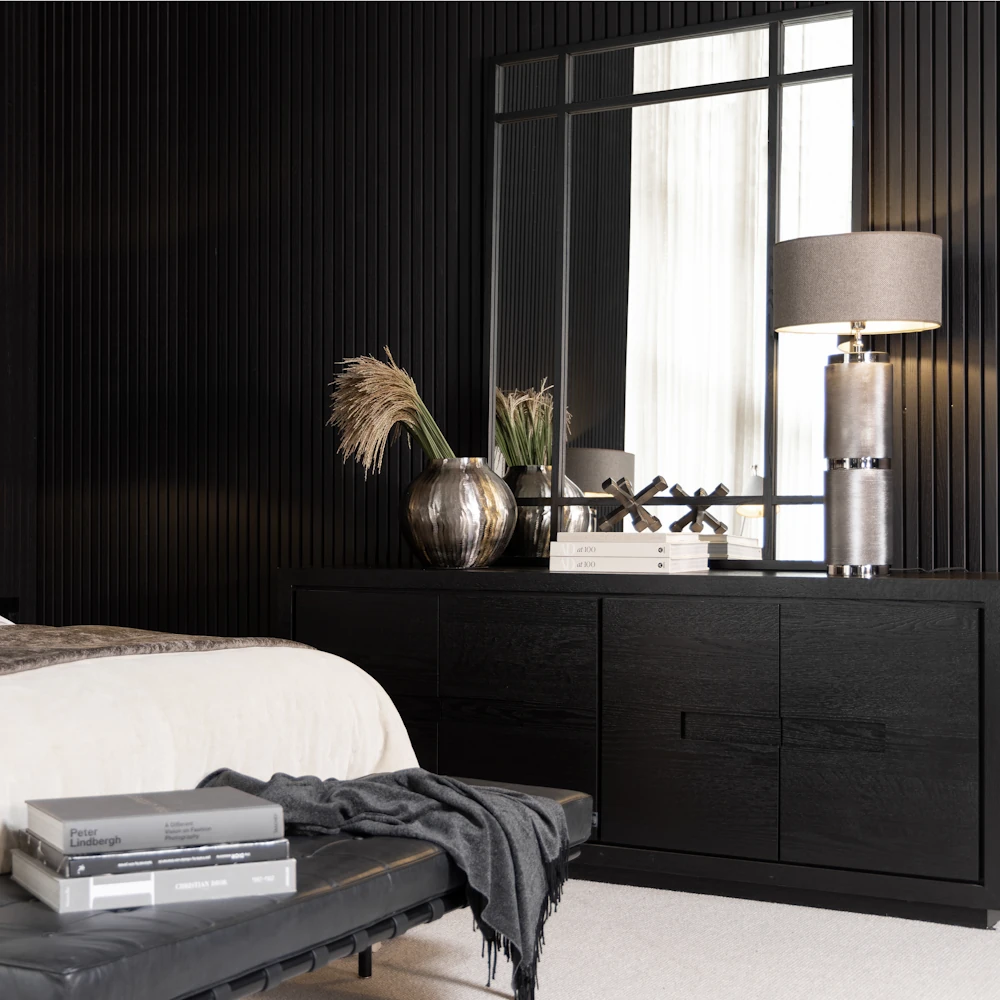 A large black mirror sitting on top of a black console in a bedroom setting.