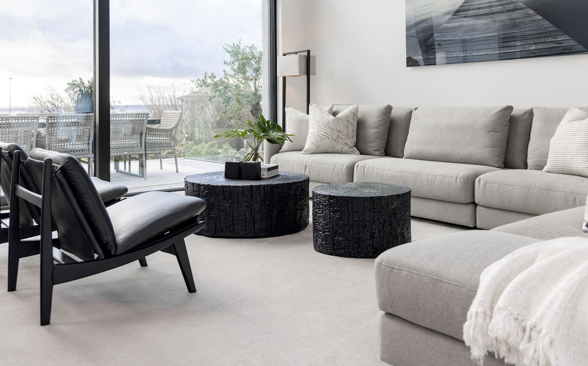 The black log coffee table and black log side table in a room setting with a light coloured fabric modular sofa.