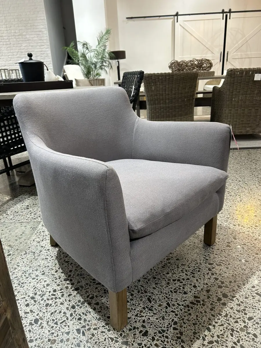 The Harbour Armchair in a linen slate grey fabric. The armchair has wooden legs and is at the Refined Living showroom.
